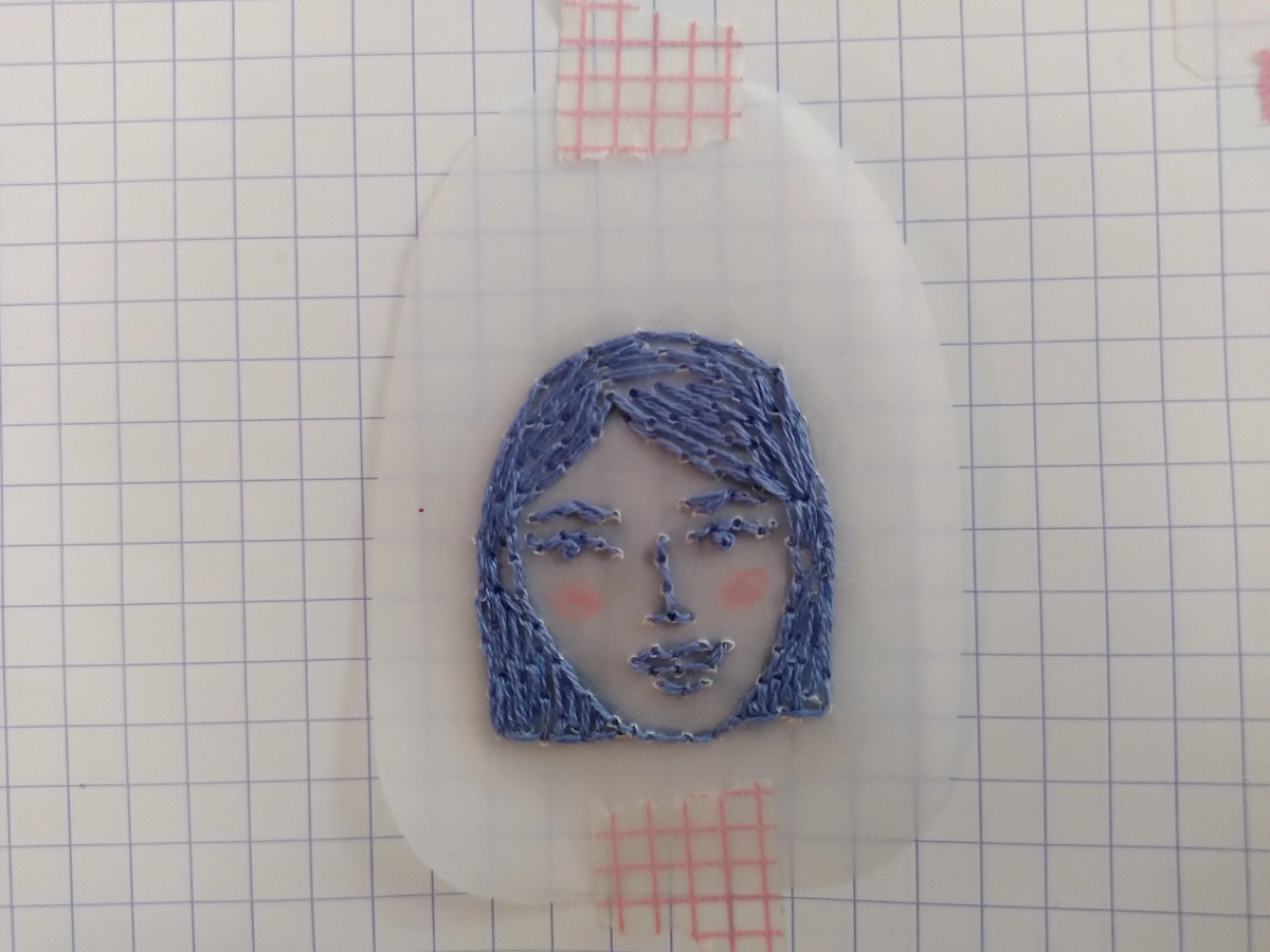 Broderie d'un visage de femme sur du papier calque